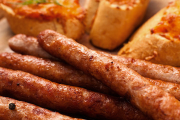 Appetizing grilled snack for beer background. Tasty golden bavarian sausages with toasts closeup, pub or restaurant menu backdrop. Junk food, german cuisine concept