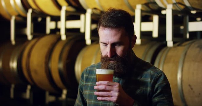 a brewmaster expert checks the quality of the freshly tapped beer from wooden barrels formerly used for flavour the wine or beer.
