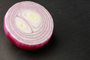Fresh slice of red onion against a black background