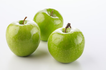 Three green apples on a white background with stem