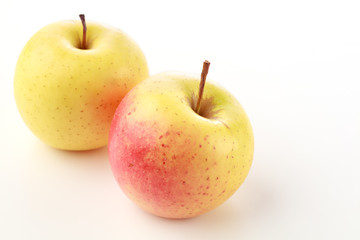 Two Yellow and pink apples against a white background with stems
