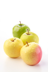 Bunch of yellow, pink and green apples against a white background