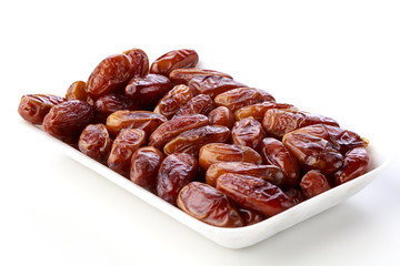 Fresh dates on a white plate against a white background