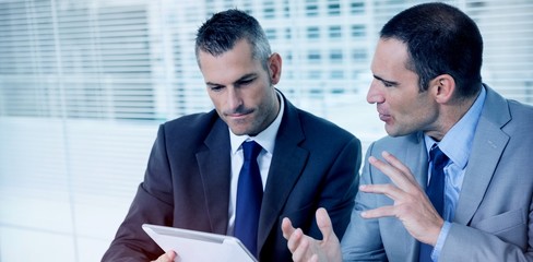 Serious businessmen analyzing documents on their tablet