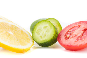 Yellow lemon, green cucumber and red tomato circular slices on a white background