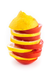 Naklejka na ściany i meble Layered slices of yellow lemon and red tomato stacked in a tower on a white background