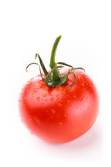 Closeup of single red circular tomato with a green stem and water droplets on a white background