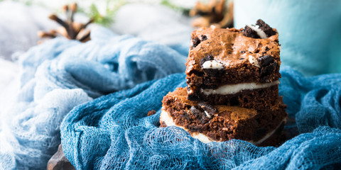 Cream cheese brownies with cookies on blue. Winter christmas treat square chocolate bars. Banner image