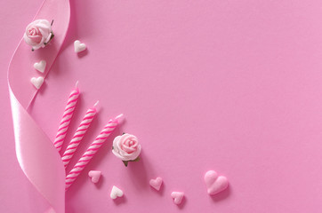 Schleifenband, Rosen, Geburtstagskerzen und Herzen auf rosa Untergrund