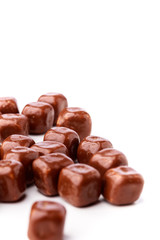 Closeup of shiny square sweet chocolates spread out on a white background