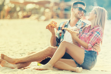 Love Couple Eating Pizza and Drinking Beer on the Beach