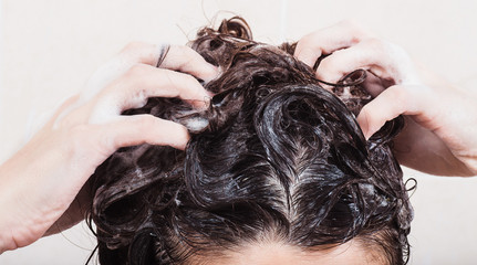 Naklejka premium Young woman washing hair with shampoo in the shower