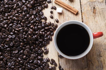 Coffee cup and coffee beans on wooden background.