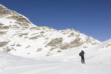 Fototapeta na wymiar Man photographing snowy landscape of Italian alps