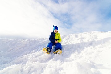 Fototapeta na wymiar Happy child sliding from little snowy hill