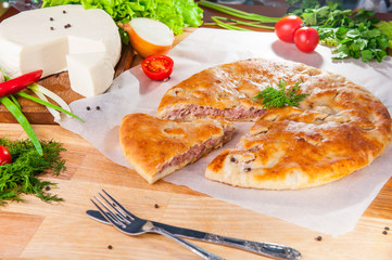 Selective Focus Traditional meat closed pie on the table. Composition of ingridients.