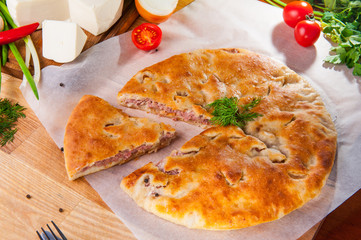 Selective Focus Traditional meat closed pie on the table. Composition of ingridients.
