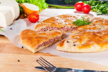 Selective Focus Traditional meat closed pie on the table. Composition of ingridients.
