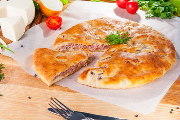 Selective Focus Traditional meat closed pie on the table. Composition of ingridients.