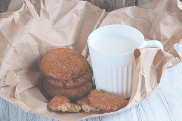Mug with milk and oatmeal cookies wrapped in paper edge