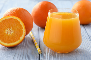 Fresh orange juice on blue wooden background.