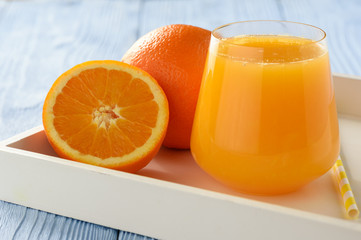 Fresh orange juice on blue wooden background.