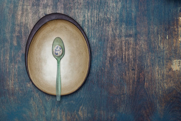 Simple still life with hand-crafted ceramic plate and quail egg on distressed wooden table.