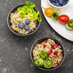 Healthy breakfast snack. Quinoa bowl with fresh vegetables, berries and herbs on a marble background in portioned bowls    . Top view