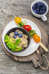 Healthy breakfast snack. Quinoa bowl with fresh vegetables, berries and herbs on a marble background in portioned bowls    . Top view