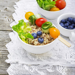 Healthy breakfast snack. Quinoa bowl with fresh vegetables, berries and herbs on a marble background in portioned bowls    . Top view