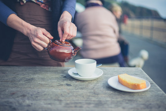 Woman pouring tea at table outside