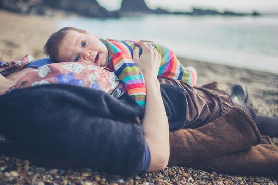 Mother relaxing on beach with baby