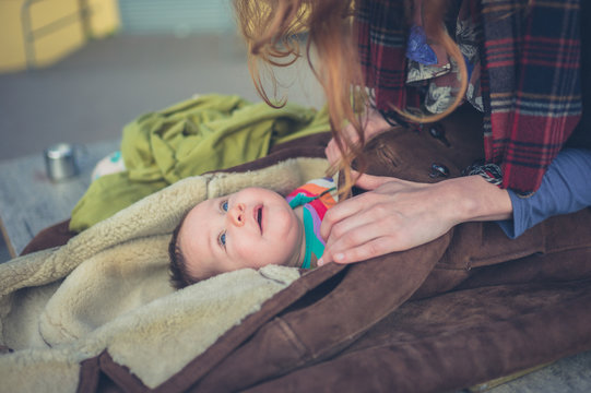 Mother wrapping baby in coat outside