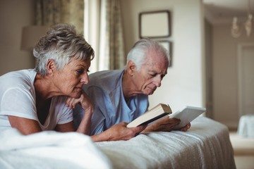 Senior woman reading and senior man looking at digital tablet