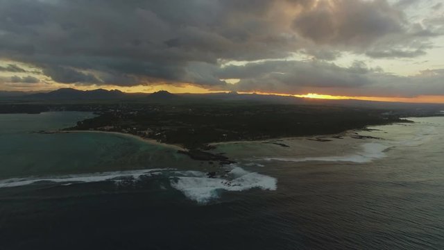 Aerial panorama of Mauritius at sunset. Island with flat green landscape and mountains on skyline surrounded with blue ocean