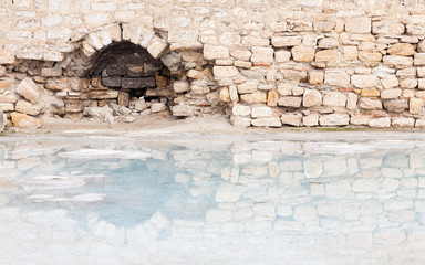 Hierapolis Hot Spring.  The view across a hot spring towards a ruined building in Hierapolis, southwestern Turkey.  The site is a UNESCO World Heritage Site. - obrazy, fototapety, plakaty