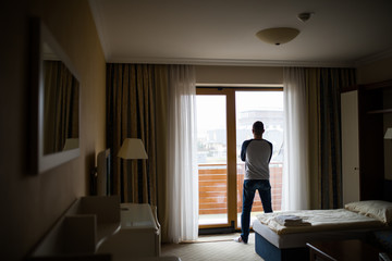Man opens curtains to look at the view from a hotel window
