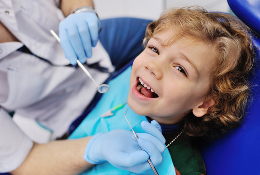 smiling child sitting in a blue chair dental