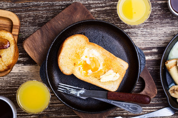 Homemade organic egg baked in toast on cast iron pan. Rustic breakfast table viewed from above