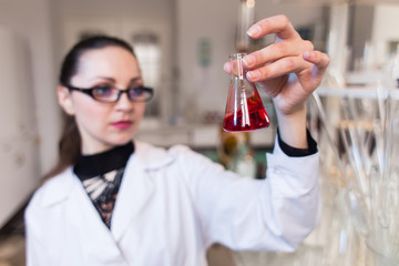 A scientist in a laboratory studying the liquid in the beaker