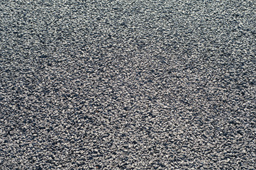 Asphalt black surface with gravel closeup as background