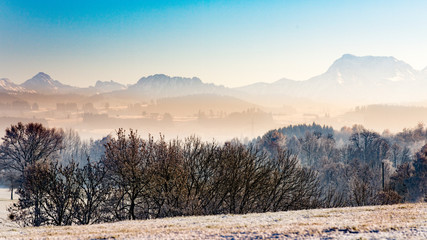 Fototapeta na wymiar Winterlandschaft dunstig und Nebel in Bayern Berge Panorama