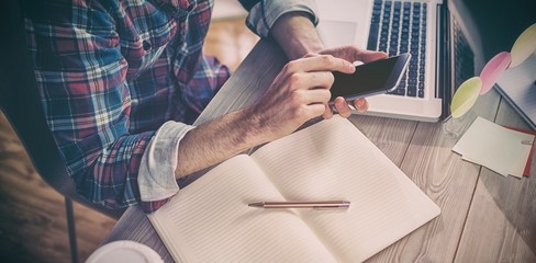 Midsection of creative editor using cellphone