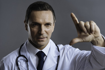 Portrait of concentrated doctor gesturing on a grey background
