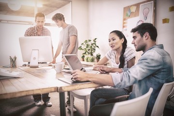 Creative business team gathered around laptops