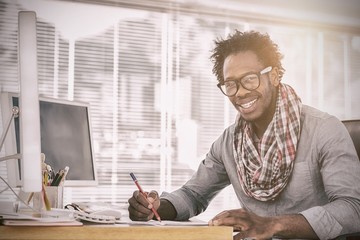 Smiling designer drawing with a red pencil on a desk