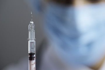 Close up of hypodermic needle being held by doctor