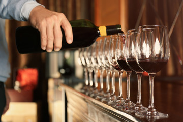 Man pouring red wine into glasses