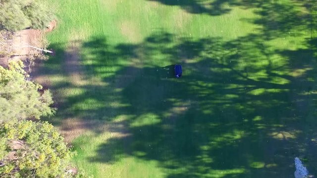 Drone aerial view of Golfers in Electric Golf Buggy with Caddy driving through Golf Course.

