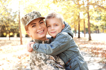 Mother soldier and little kid embracing in the park